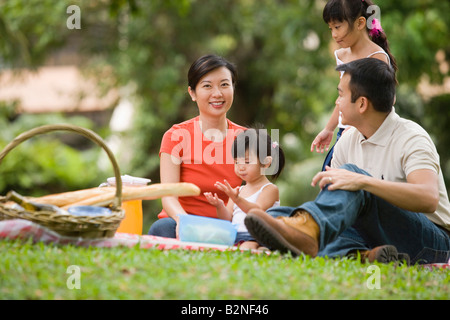 Mitte erwachsenes paar mit ihren beiden Töchtern mit Picknick in einem Park, Singapur Stockfoto