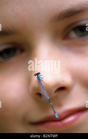 Junges Mädchen 11 Jahre alt mit Damselfly auf der Nase, Blick in die Kamera Stockfoto