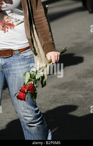 Detail der Frau mit drei roten Rosen in der Stadt Stockfoto