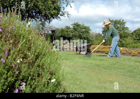 Frau mit Hut Rechen den Rasen im Garten Stockfoto