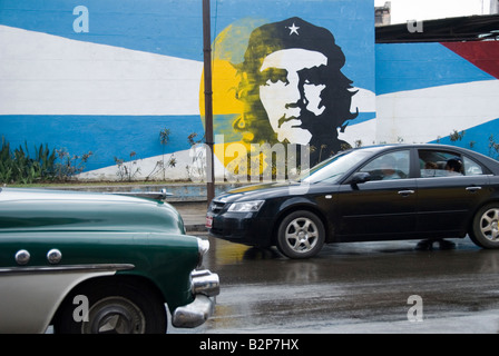 Oldtimer und Neuwagen vorbei ein Wandbild von Ernesto Che Guevara während der Zeit des Embargos in Centro Habana Cuba Kuba Stockfoto