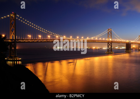 Bay Bridge San Francisco leuchtet in der Dämmerung mit Verkehr Rückleuchten aus roten Bändern über seine Spannweite Stockfoto