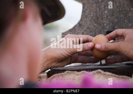 Ein Tourist auf der Solar Museum Intinian auf der Äquatorlinie versucht, ein Ei auf dem Nagel in der Nähe von Quito in Ecuador zu balancieren. Stockfoto
