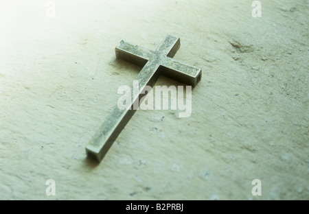 Einfache angelaufener Messing Kruzifix auf Creme liegend bemalten Stein Fensterbank oder Nische Stockfoto