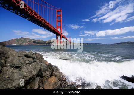 Surf plätschert über die Felsen unter der Golden Gate Bridge von Fort Point Strand aus gesehen Stockfoto