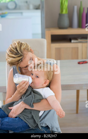 Mutter Küsse und Flasche füttert baby Stockfoto