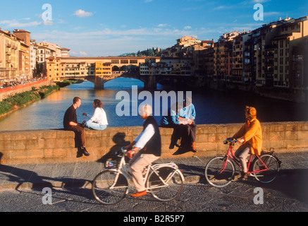 Paare sitzen und Radfahren am Ponte Sankt Trinita über Fluss Arno in Florenz Italien Stockfoto
