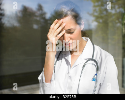 Junge Ärztin am Fenster Stockfoto