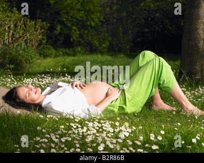 Schwangere Frau im Garten, Lächeln Stockfoto