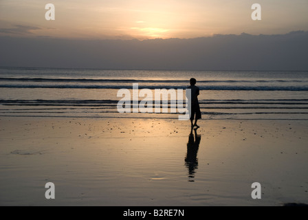 Kuta Bali Indonesien Badebucht Meer Surf Sonnenuntergang Mann Frau zu Fuß Kontemplation Wolke Himmel Wellen kräuseln Reflexion Silhouette Stockfoto