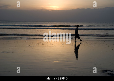 Kuta Bali Indonesien Badebucht Meer Surf Sonnenuntergang Mann Frau zu Fuß Kontemplation Wolke Himmel Wellen kräuseln Reflexion Silhouette Stockfoto