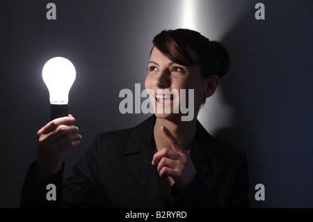 Geschäftsfrau im Alter von 24 mit einer Glühbirne in der hand Stockfoto