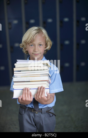 Schuljunge holding Stapel Bücher Stockfoto