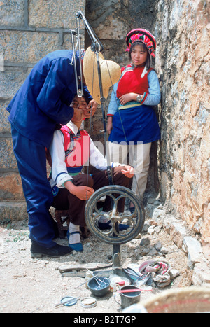Zahnarzt mit Assistent arbeitet auf Patienten in Hill Tribe Marktplatz mit Fuß angetrieben Handbohrer in der chinesischen Provinz Yunnan Stockfoto