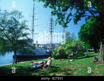 Paare auf dem Rasen romantischen Sommer Momente neben Af Chapman Schoner vor Anker auf der Insel Skeppsholmen in Stockholm Stockfoto