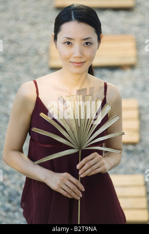 Frau mit getrockneten palm Leaf, lächelnd in die Kamera Stockfoto