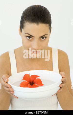 Frau mit Hibiskusblüte in Schüssel mit Wasser, in die Kamera Lächeln Stockfoto