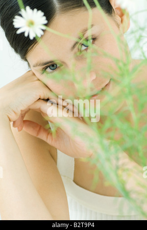 Frau hinter Kamille Pflanze, lächelnd in die Kamera, Porträt Stockfoto