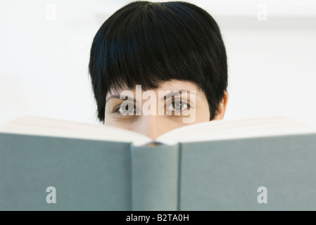 Frau blickte über Buch in die Kamera Stockfoto