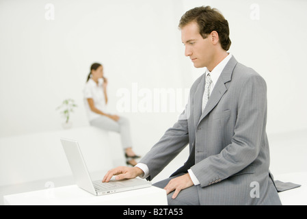 Professionelle Mann mit Laptop-Computer, Kollegin im Hintergrund Stockfoto