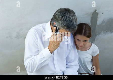 Vater und Tochter sitzen zusammen, Mann auf Handy, Blick nach unten Stockfoto