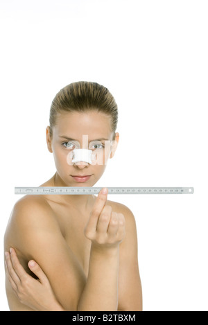 Frau mit verbundenem Nase, Lineal, Blick in die Kamera hält Stockfoto