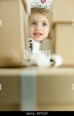 Mädchen wie eine Prinzessin, spähte durch Stapel von Geschenken Stockfoto