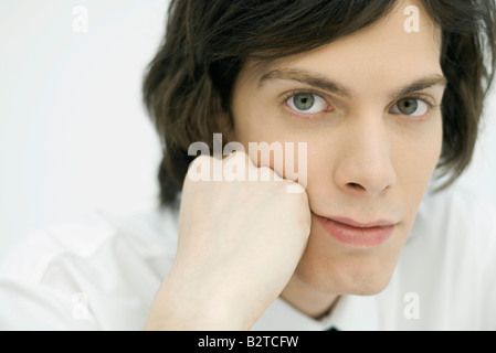 Junger Mann hielt Kopf, Blick in die Kamera, Porträt Stockfoto