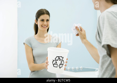 Mann mit dem Ziel Papierkugel in Richtung Recyclingbehälter in Weibes Armen, beschnitten, Ansicht Stockfoto