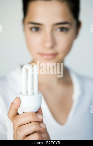 Junge Frau mit Energie effiziente Glühbirne, Fokus auf Vordergrund Stockfoto