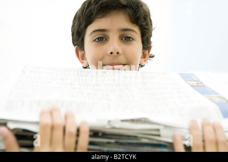 Junge hält hohen Stapel Zeitungen, lächelnd in die Kamera Stockfoto