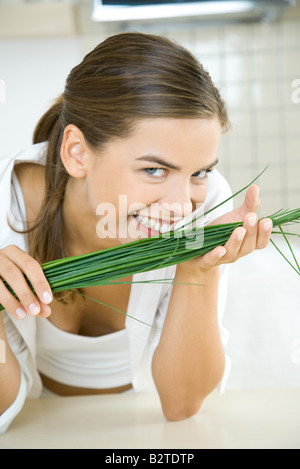 In die Kamera lächelnde Frau riecht frischer Schnittlauch Stockfoto