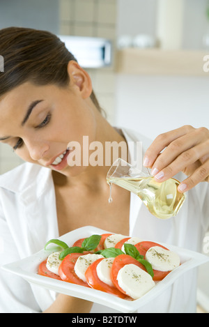Frau, gießen Öl auf Antipasti Stockfoto
