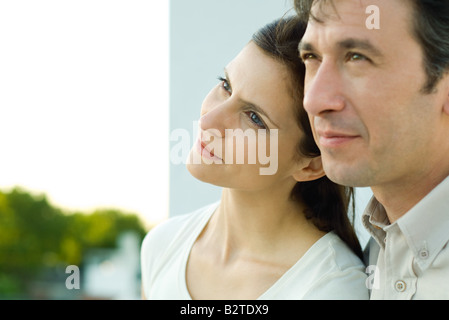Frau lehnte ihren Kopf gegen Mannes Wange, beide wegschauen Stockfoto