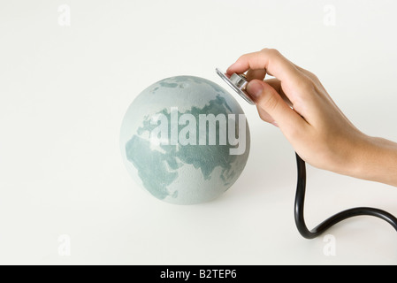 Hand mit Stethoskop bis zu Globus, beschnitten Stockfoto