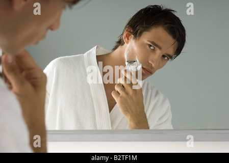 Man betrachtet sich im Spiegel, rasieren, Bademantel tragen Stockfoto