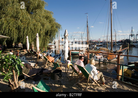 Leute sitzen in Liegestühlen am Hafen, Leute sitzen in Liegestühlen am Sandstrand open-air-Gelände des Restaurant in Övelgönne, Schinken Stockfoto