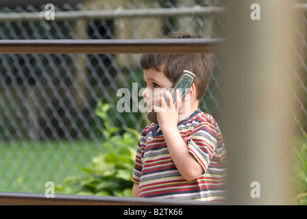 Drei Jahre alte junge Gespräche über Handy außerhalb seiner Lieblings-Spielplatz Stockfoto