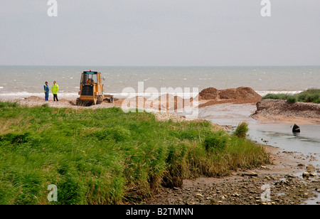 Eine Raupe/Bagger bei der Arbeit - Entwässerung am Strand für einen blockierten Fluss und anschließende Land Flut zu schaffen. Stockfoto