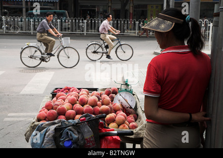 Eine einheimische Frau mit Obst auf den Straßen von Peking in China. Stockfoto