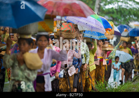 Prozession der Frauen, die Hindu-Angebote in Körben auf ihren Köpfen während ein tropischer Sturm in Bali Indonesien Stockfoto