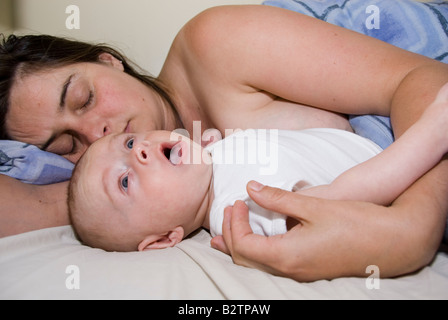 Gähnende Baby Boy Joshua Kailas Hudson im Alter von 15 Wochen im Bett mit schlafen Mutter Deborah Wasser Stockfoto