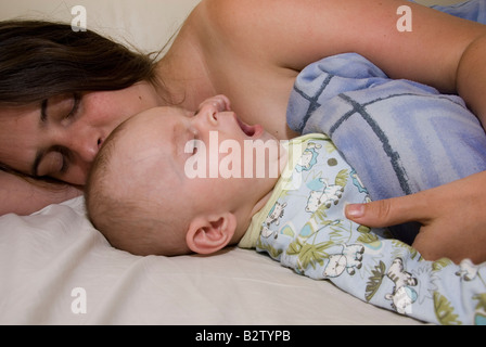 Gähnende Baby Boy Joshua Kailas Hudson im Alter von 15 Wochen kuscheln, schlafen im Bett der Mutter Deborah Wasser Stockfoto