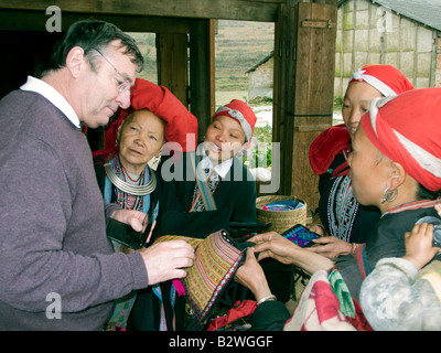 Red Dzao Bergvolk Frauen pochen Runde Touristen und Touristenbusse Kunsthandwerk Ta Phin Dorf in der Nähe von Sapa Vietnam zu verkaufen Stockfoto