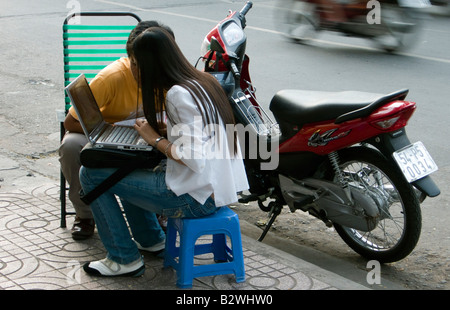 Junge Frau nutzt Computer außerhalb auf Pflaster Ho-Chi-Minh-Stadt Hauptstadt Vietnam Stockfoto