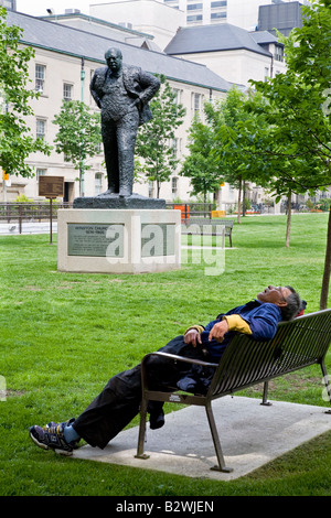 Sir Winston Churchill-Statue am Nathan Phillips Square mit schlafenden Mann auf Bank. Toronto, Ontario, Kanada. Stockfoto