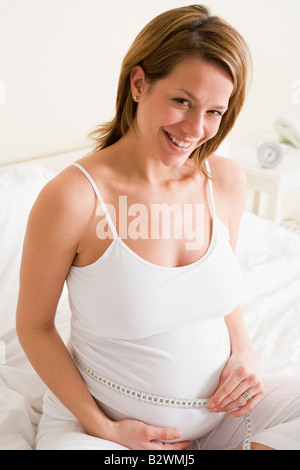 Schwangere Frau im Schlafzimmer Mess Bauch Lächeln Stockfoto