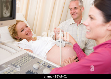 Schwangere Frau immer Ultraschall vom Arzt mit Mann beobachten Stockfoto