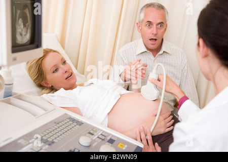 Schwangere Frau immer Ultraschall vom Arzt mit Mann beobachten Stockfoto