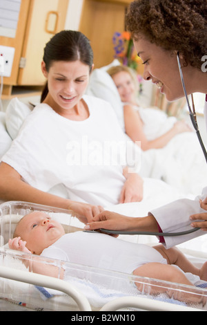 Arzt überprüft Baby Herzschlag mit neuen Mutter beobachtete und lächelnd Stockfoto